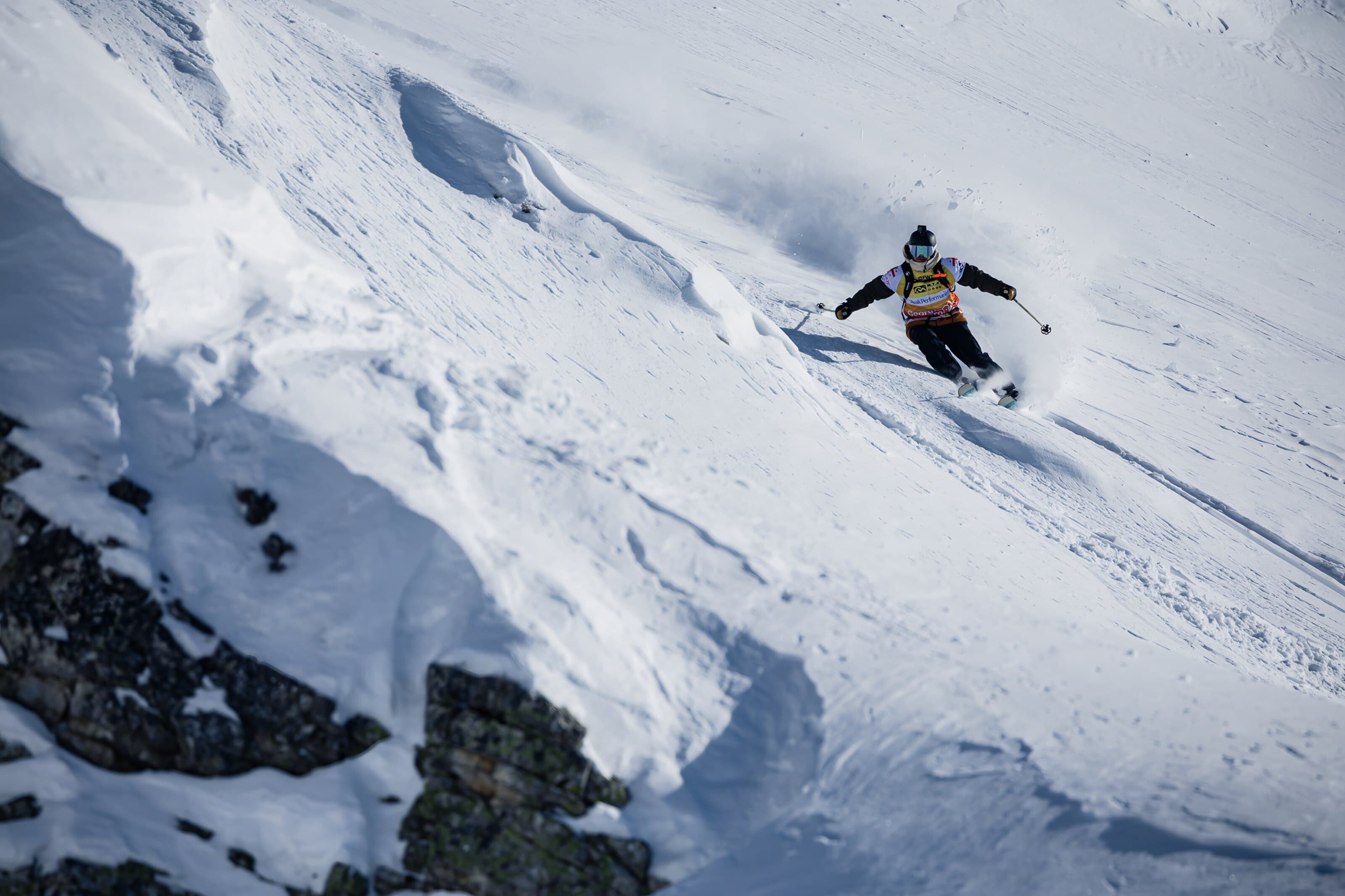 A skier mid run on a steep competition face