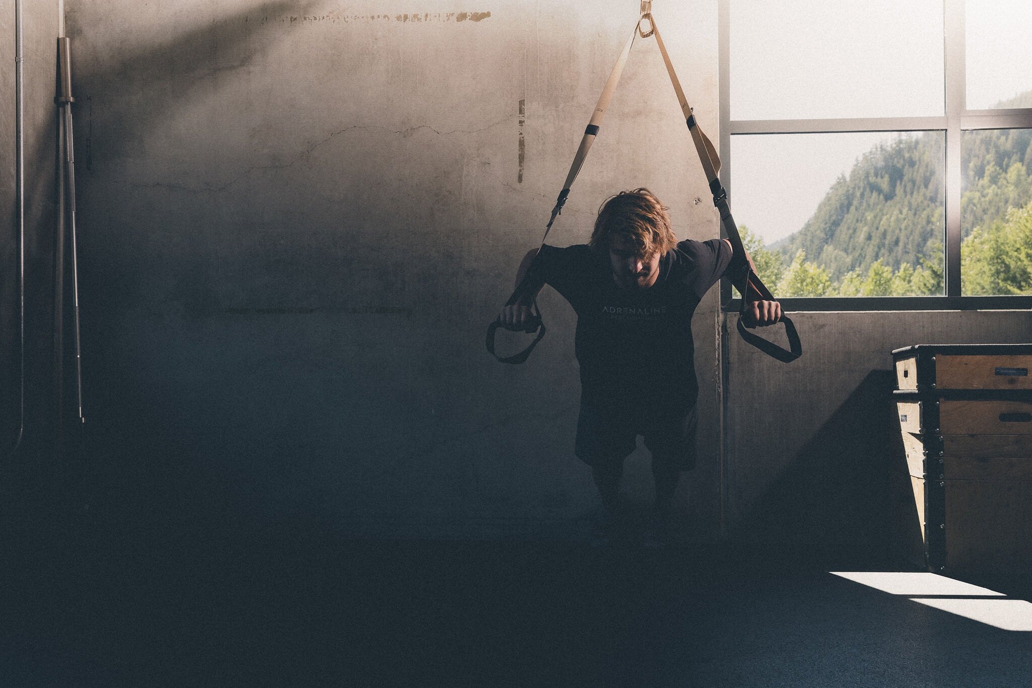A skier pressing out on suspension straps in a dark gym
