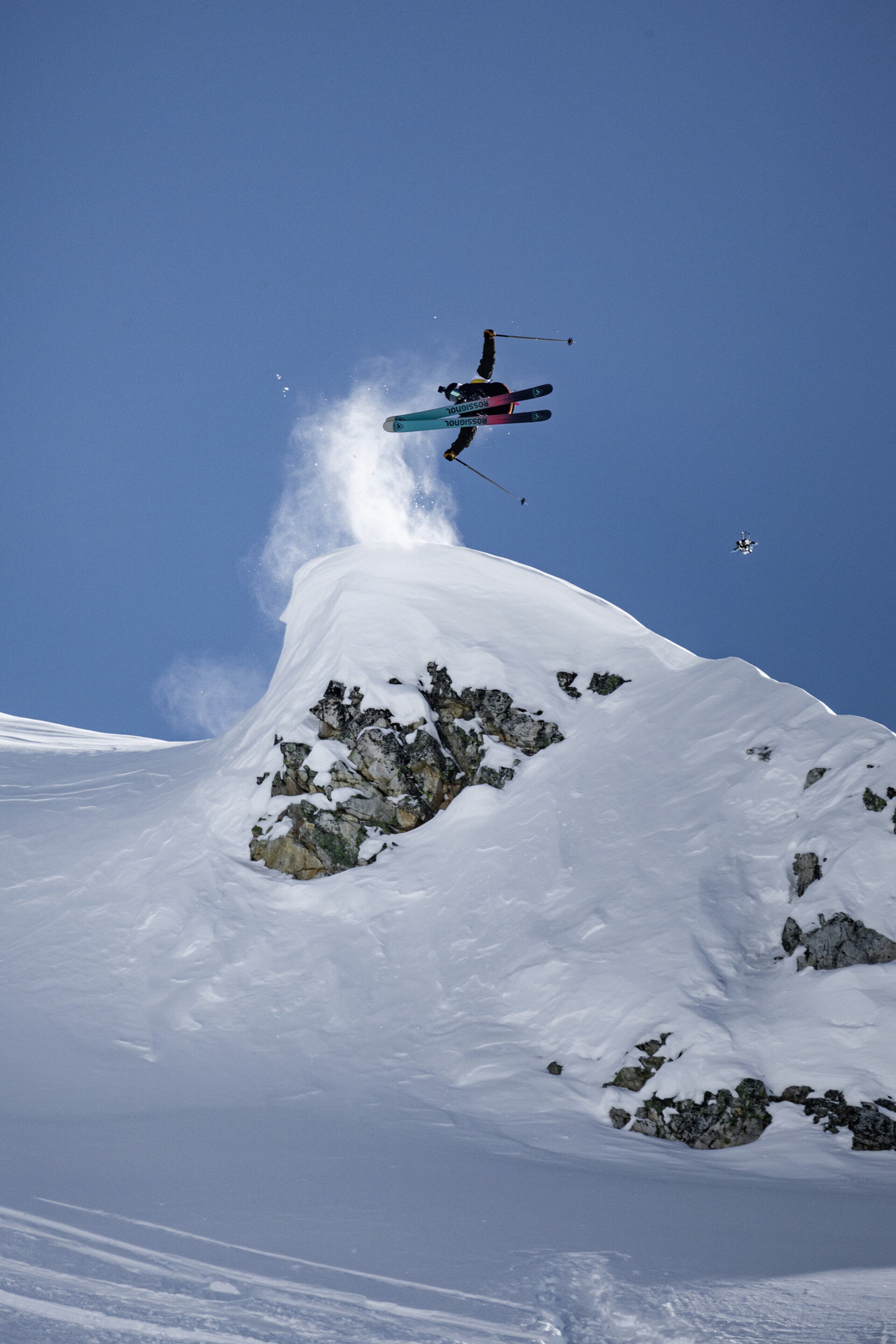 A skier launching off a cliff on a big mountain line