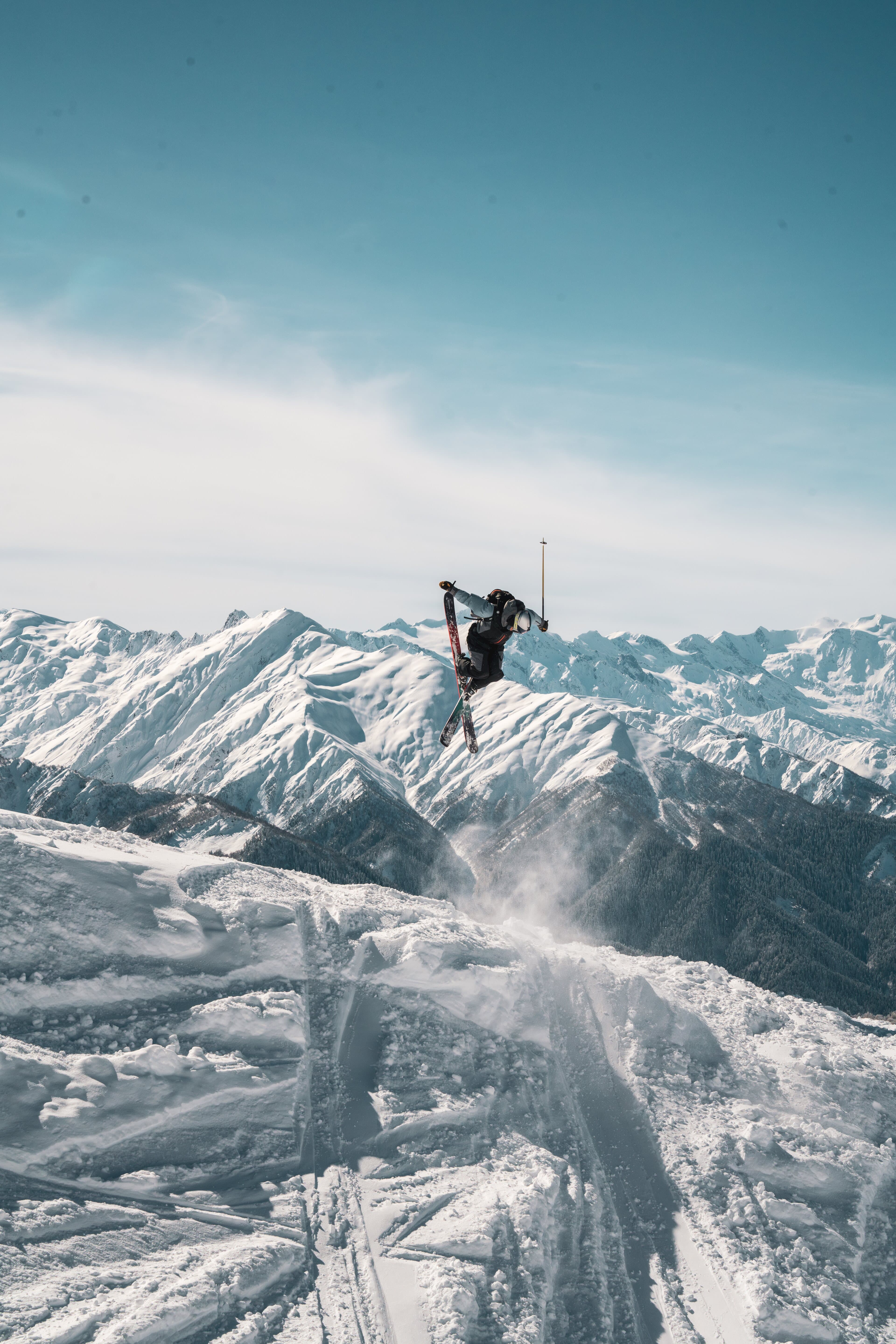 A skier upside down in the air above a range of snowy peaks