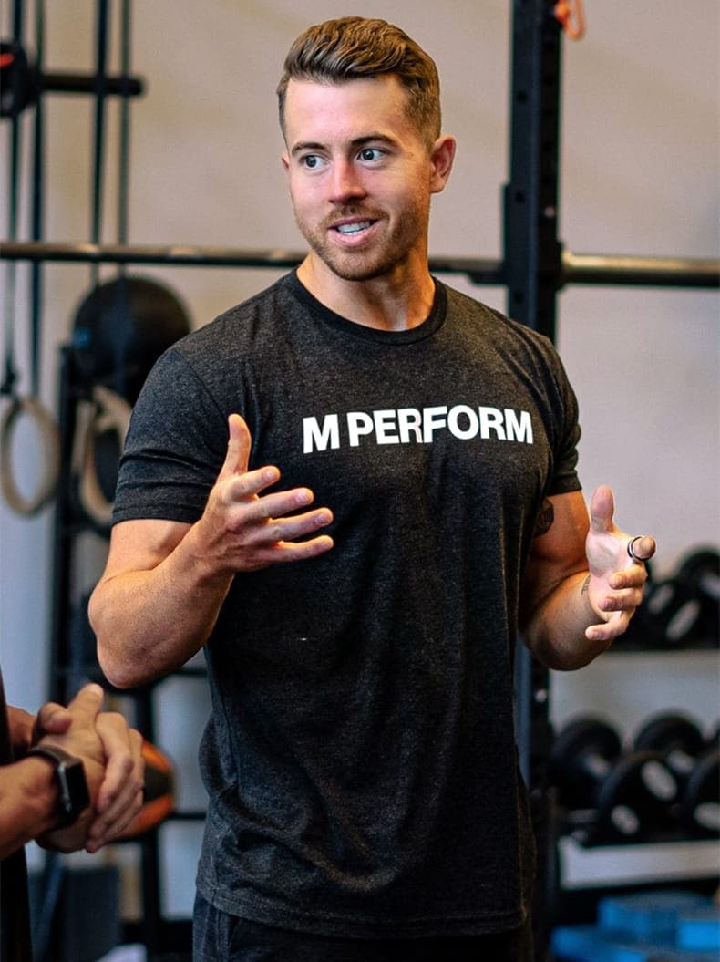Marcus Mackay coaching in a gym, in an M PERFORM shirt