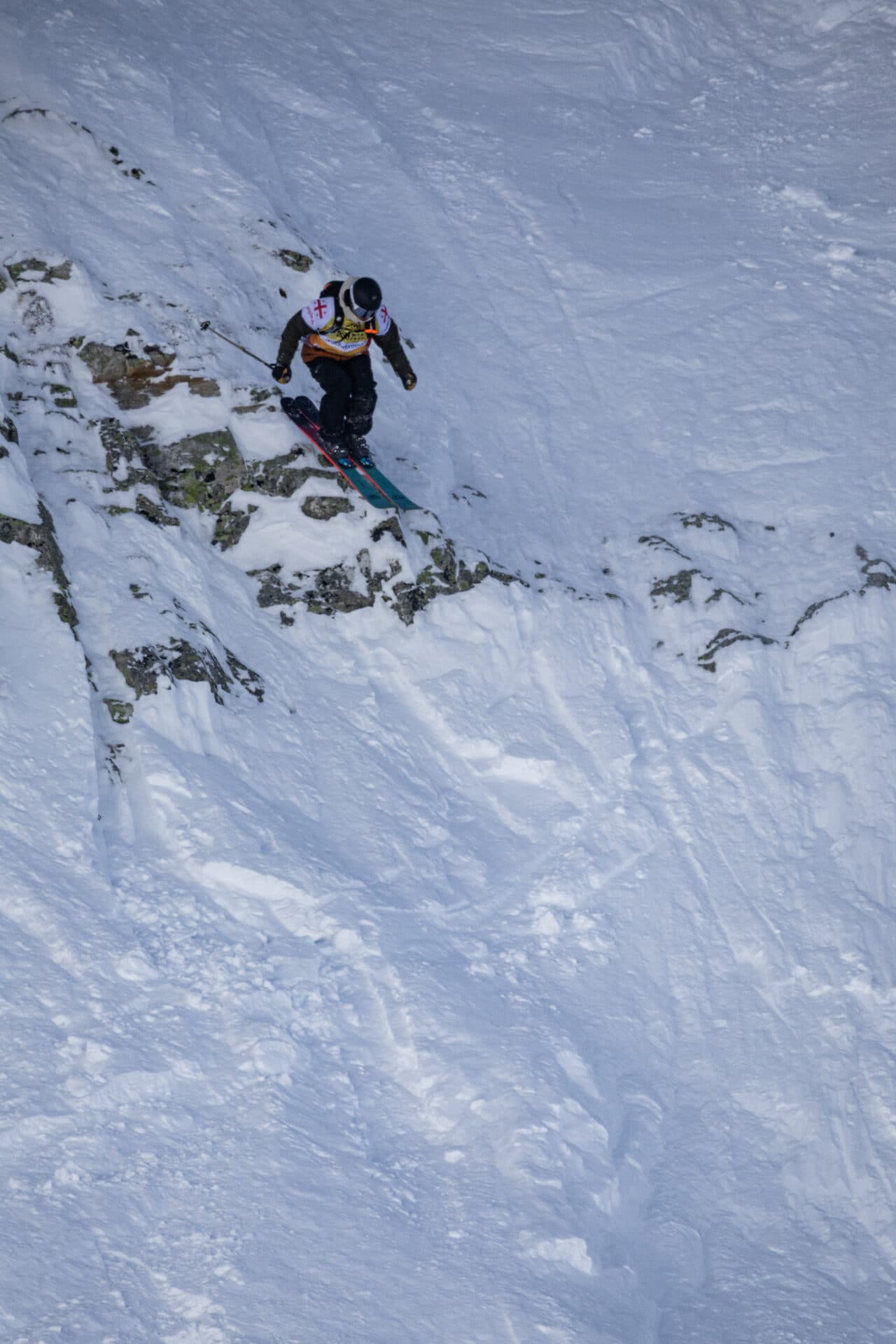 A skier in the air off a rock band on the Georgia Pro face